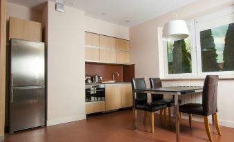 a kitchen with wooden cabinets , a dining table and chairs , and a refrigerator in the background at Best East