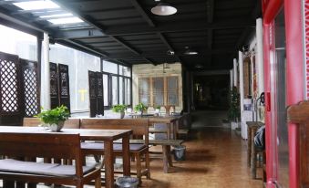 There is a restaurant in the middle with wooden tables and chairs, as well as an open doorway at Paoju Factory Youth Hostel (Beijing Summer Palace Subway Station Branch)