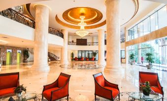 a large hotel lobby with two red chairs placed in front of a large chandelier at Sai Gon Ha Long Hotel