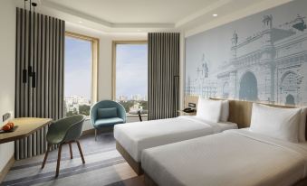 a hotel room with two beds , a chair , and a window overlooking the city view at Novotel Mumbai Juhu Beach