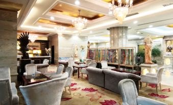 a luxurious living room with a high ceiling , chandeliers , and large couches , as well as dining tables and chairs at Relax Hotel