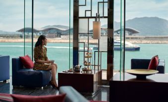 A woman is sitting at a table, facing a room with large windows at Hong Kong SkyCity Marriott Hotel