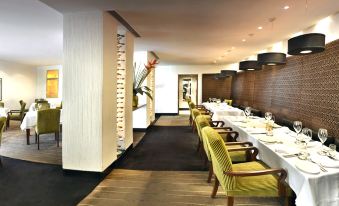 a dining room with multiple tables and chairs arranged for a group of people to enjoy a meal together at The Manor - New Delhi