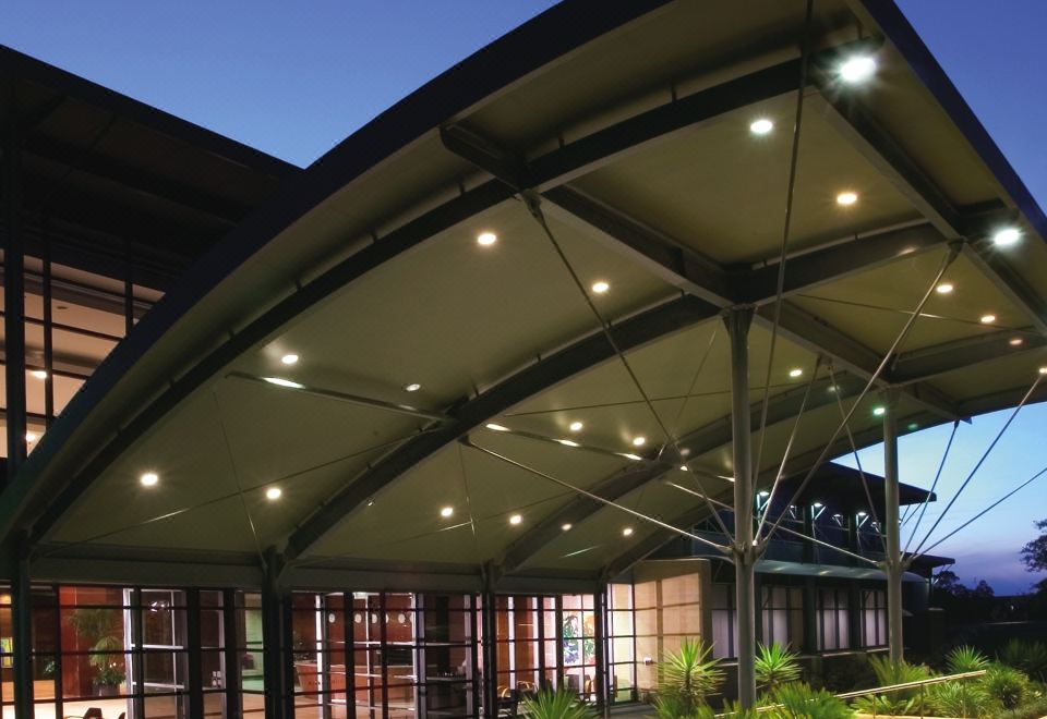 a large building with a curved roof is illuminated by lights at night , surrounded by plants and trees at Aitken Hill