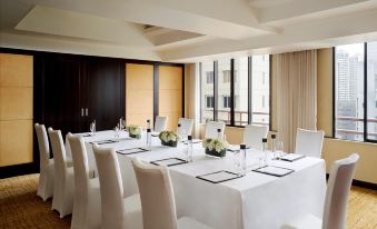 A spacious room is arranged with white tables and chairs for formal dining or events at The Portman Ritz-Carlton, Shanghai