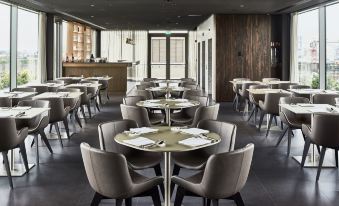 a modern restaurant with several tables and chairs , a bar area , and a high ceiling at Hotel Viu Milan, a Member of Design Hotels