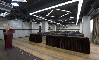 The room is spacious with black and white ceiling lighting, tables arranged for an event, and a stage positioned at the front at DCC Hotel (Guangzhou Tianhe Coach Terminal Station)