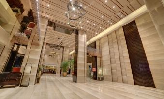 a large , well - lit hotel lobby with marble floors and walls , as well as a reception desk and several chairs at Fuzhou Hotel