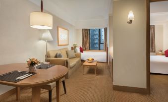 The room is furnished with a couch, table, and chairs, and it features large windows that provide a view of the living area at Ramada Hong Kong Grand View