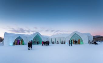 a group of people standing outside a snow - covered building , possibly an ice hotel , on a sunny day at Hôtel de Glace