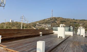 a wooden deck with a view of a hill and a power line tower in the background at Dongji Island Dongguan Hotel