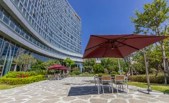 There is a patio with tables and chairs under an umbrella located on the sidewalk at Hisilk Artwork Center Fliport Coso Hotel