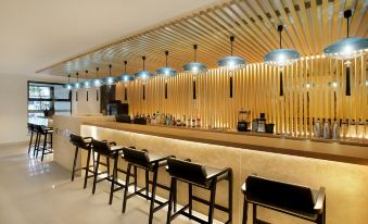 The restaurant's bar is adorned with a diverse selection of unique lighting, creating an intriguing ambiance at Ginco Hotel