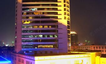 a tall building with yellow lights illuminating it at night , creating a festive atmosphere in the city at Phoenix Hotel