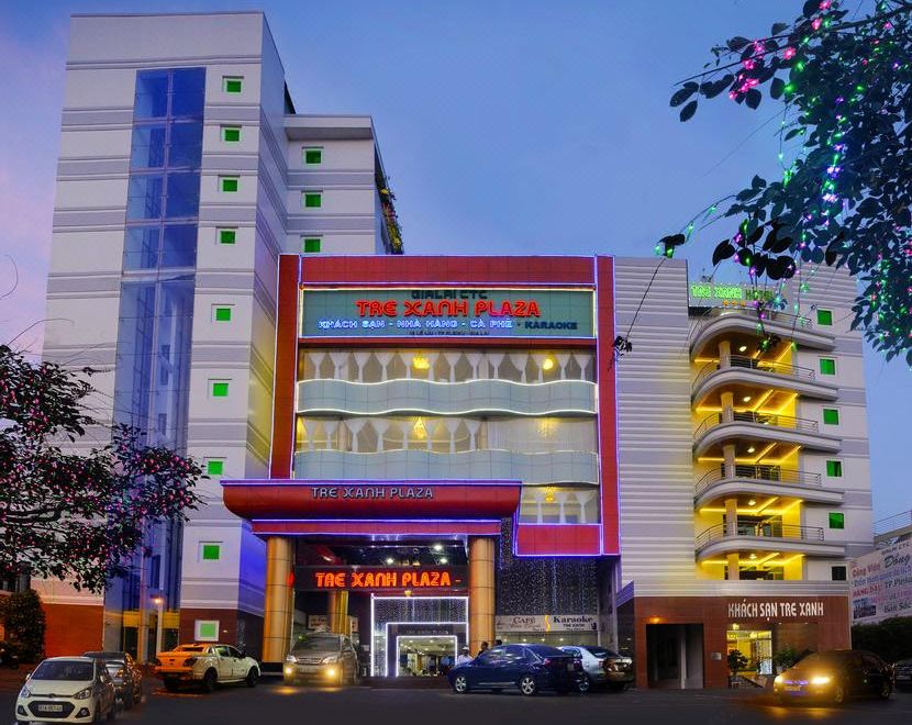 a modern building with a red and white exterior , lit up at night , surrounded by trees at Tre Xanh Hotel