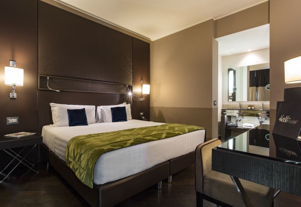 a large bed with a green blanket and white pillows is in a room with dark wood furniture at Rome Times Hotel
