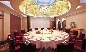 a large round table is set with white tablecloths and place settings in a room with red chairs at Central Hotel