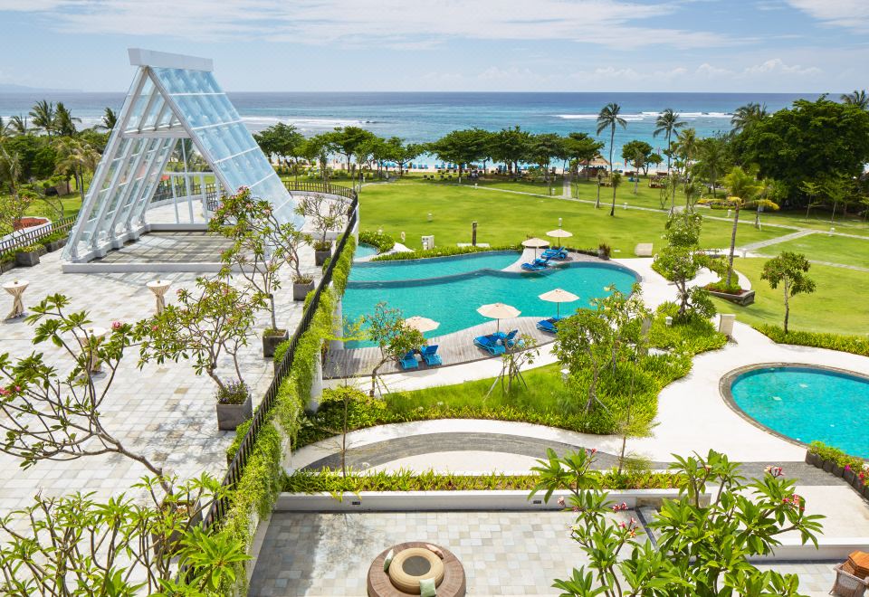 a large outdoor pool area with a unique design and surrounding greenery , overlooking the ocean at Merusaka Nusa Dua