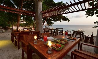 an outdoor dining area near the ocean , with tables and chairs arranged for a meal at Sai Daeng Resort