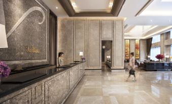 a modern hotel lobby with marble floors , a reception desk , and a person walking through the area at Hotel Valletta