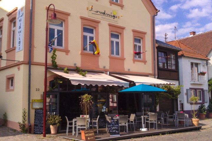 a small restaurant with a yellow banana on the sign , surrounded by several tables and chairs at LUDWIGS