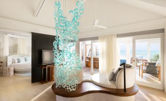 a modern living room with a large chandelier hanging from the ceiling , creating an elegant and sophisticated atmosphere at Lux* South Ari Atoll