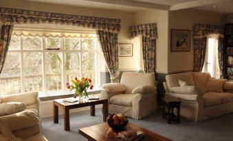 a cozy living room with a large window , white couches , and a wooden coffee table at Lydgate House Hotel