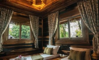 a cozy wooden room with two beds , curtains , and a chandelier , providing a comfortable living space at Khum Wang Nuea Villa