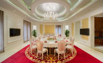 The room is spacious and elegantly decorated with red carpet, a chandelier, and a round table that can accommodate six people at Bai Fu Yi Hotel