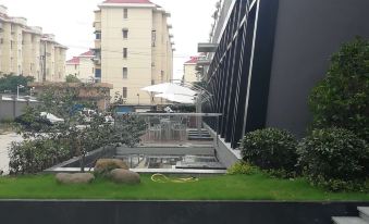 There is a courtyard with grass and buildings in the background, including an apartment building on one side at Sky Bird Hotel (Shanghai Hongqiao Airport)