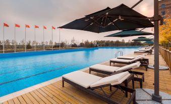 The hotel features a spacious swimming pool area with comfortable lounge chairs and umbrellas at Guoce International Conference and Exhibition Center