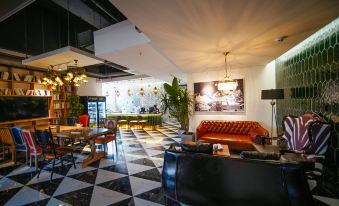 The lobby features a restaurant with tables and chairs, as well as an open concept floor-to-ceiling window, offering guests a distinctive dining experience at POSHPACKER Local Tea Hostel