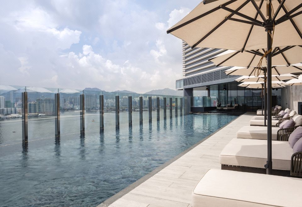 The elevated rooftop offers a swimming pool with chairs and umbrellas, providing a scenic view of the city at Hyatt Centric Victoria Harbour Hong Kong