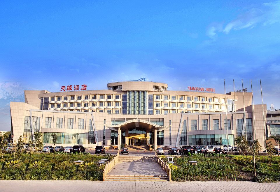 The ornate building can be seen from the front view across a large parking lot at dusk at Tianyuan Hotel