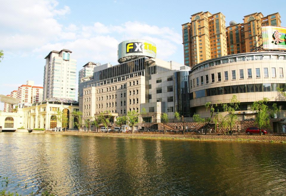 There is a large body of water with buildings in the background, including an oriental-style building at FX Hotel (Beijing Yansha)