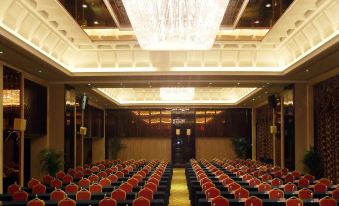 There is a large conference room with rows of auditorium chairs facing the front and chandeliers on either side at Wansheng International Hotel