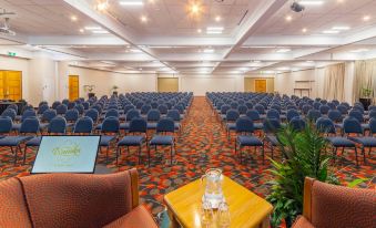 a large , empty conference room with rows of blue chairs and a laptop on a table at Wairakei Resort Taupo