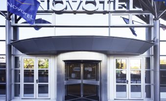 "the entrance of a hotel with the word "" novotel "" written above the door and two blue flags hanging above it" at Novotel Paris 14 Porte d'Orleans