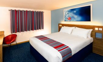 a hotel room with a king - sized bed and a tv mounted on the wall above it at Travelodge Southport