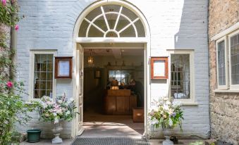 a white brick building with an arched doorway and two potted plants on either side of the entrance at Spread Eagle Inn