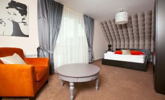 a hotel room with a large bed , a couch , and a dining table in the living area at Best East