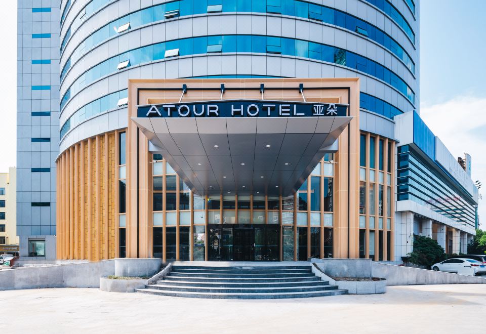 The front entrance of a hotel in an urban setting features large glass and steel doors at Atour Hotel (Yiwu International Trade City)