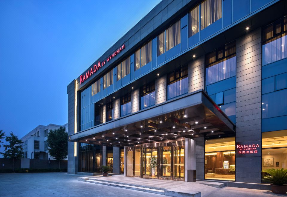 The hotel's front entrance is shown in a time-lapse video at night, featuring an illuminated sign above it at Ramada by Wyndham Beijing Airport