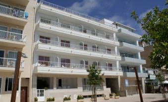 a large white apartment building situated on the side of a street , surrounded by trees at Cala Bona