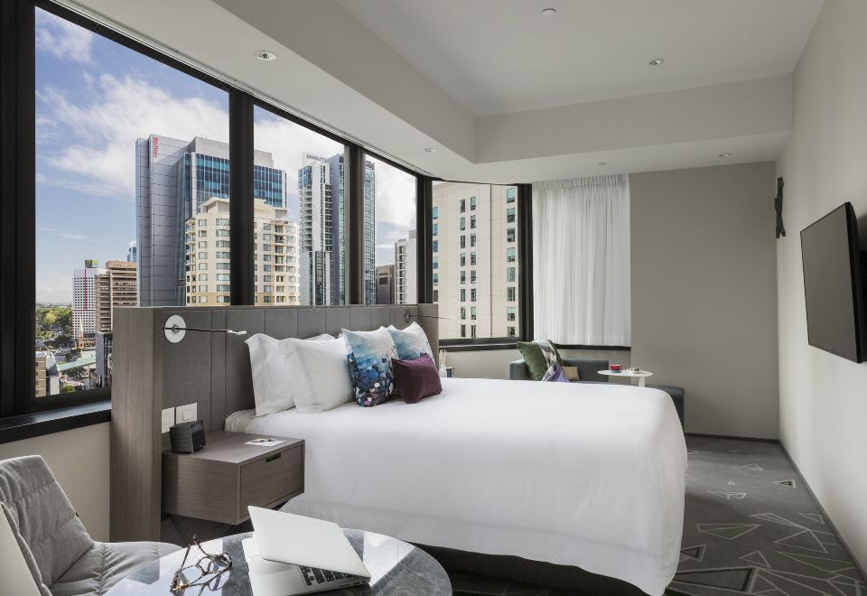 a large bed with white linens is situated in a modern hotel room with a city view at Capri by Fraser Brisbane