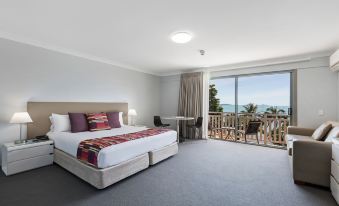 a spacious bedroom with a large bed and a view of the ocean through a window at Airlie Beach Hotel