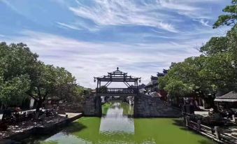 a scenic view of a canal with green water and an archway bridge , surrounded by trees and buildings at yhz