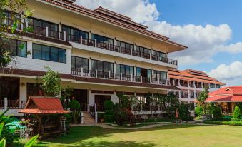 a large , multi - story building with balconies and greenery in front of it , under a blue sky with clouds at Chiangkhan River Mountain Resort