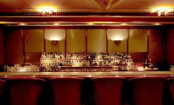 a long bar with numerous bottles and glasses on display , as well as several chairs placed around the room at Keio Plaza Hotel Hachioji