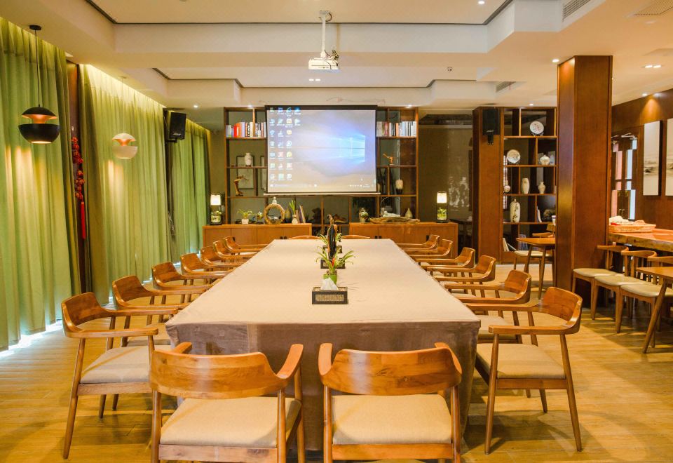 a conference room with a long table and chairs , a projector screen , and a bookshelf at Gengting Hotel